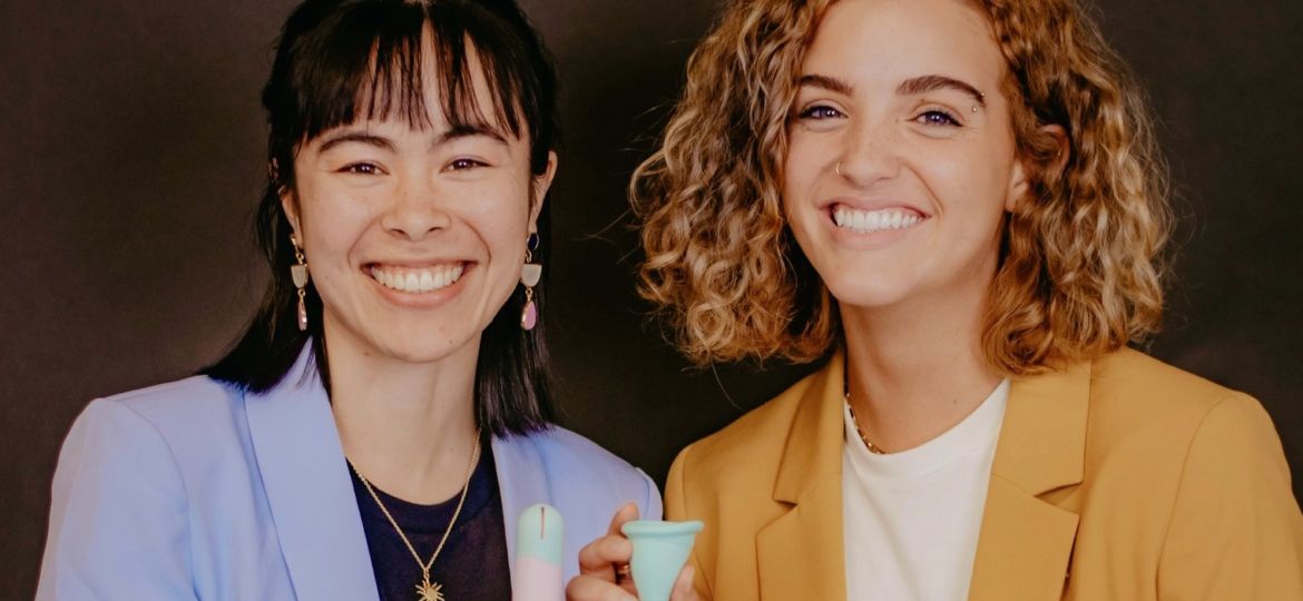 two women smiling holding reusable menstrual cups