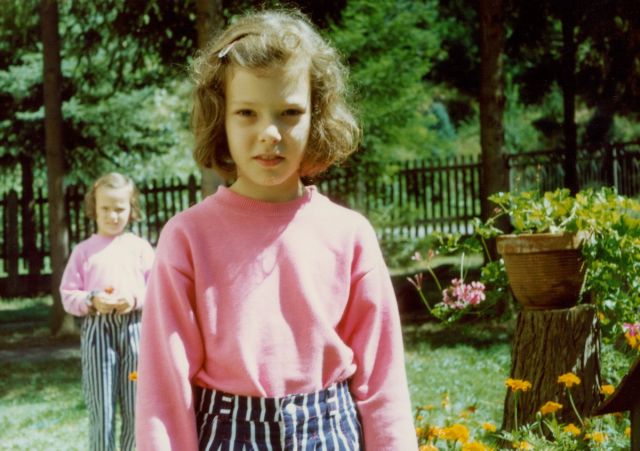 little girl wearing pink swear and blue and white striped pants with curly brown hair