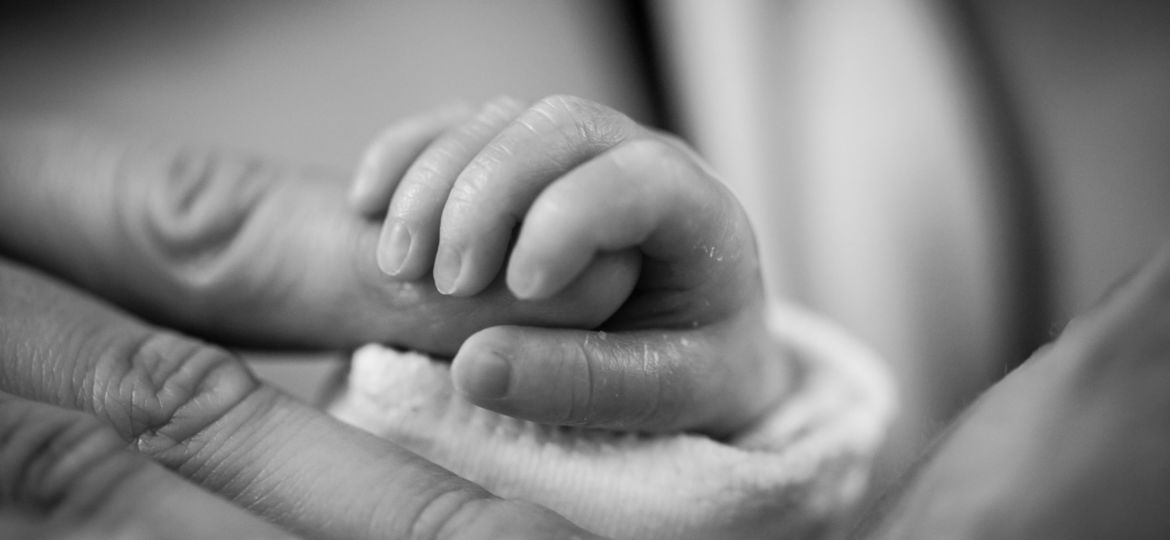 A baby holding a woman's finger