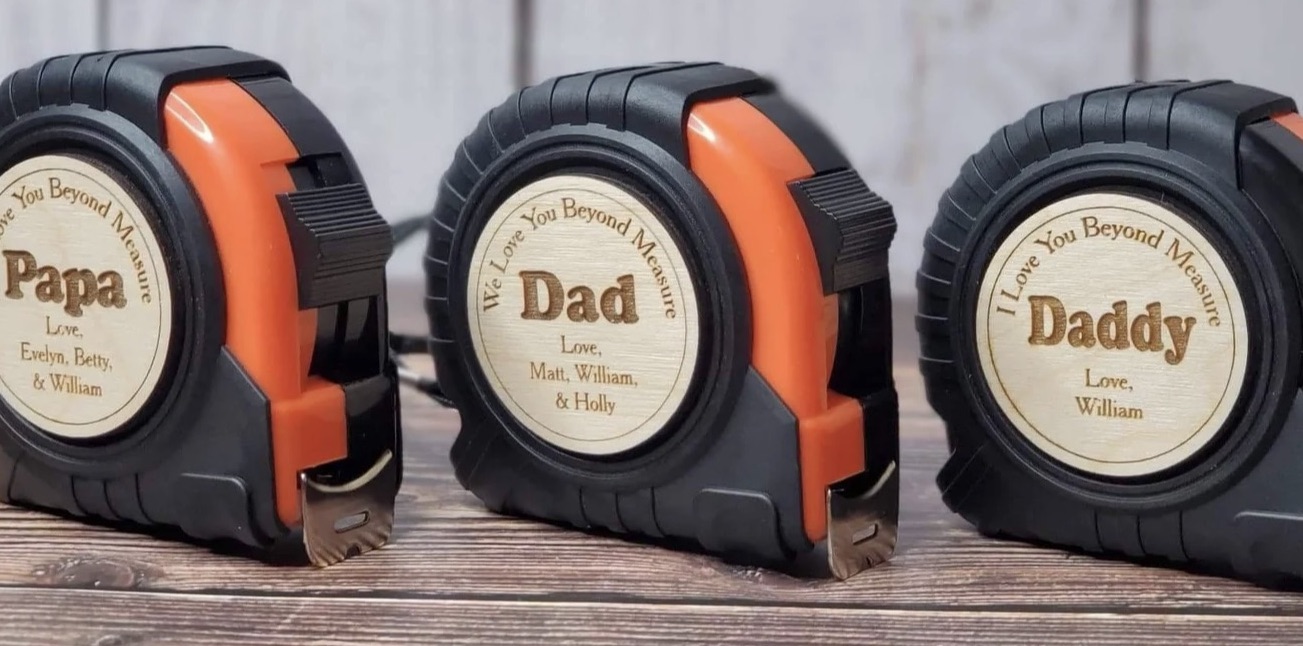 three black tape measure's that have orange tape and say "dad" on them