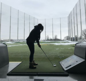 woman hitting golf ball in indoor golf company