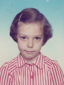 little girl in red and white striped collared shirt with pixie haircut