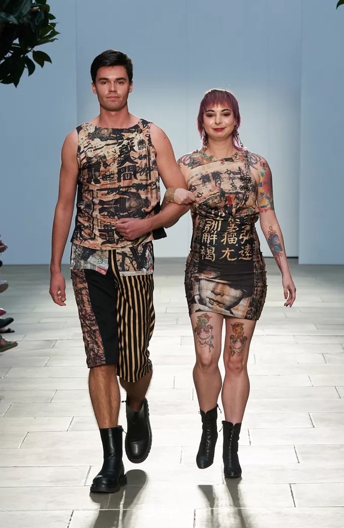 Asian woman and man wearing printed multicolor clothing walking down a runway for fashion show