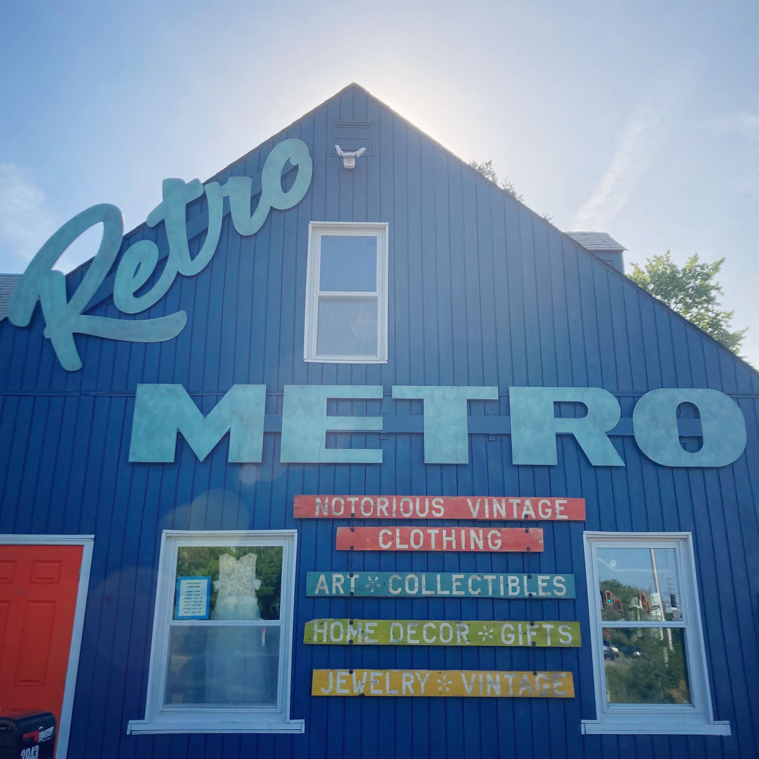 blue wooden building with orange and green and yellow signs on it and a blue logo reading retro metro