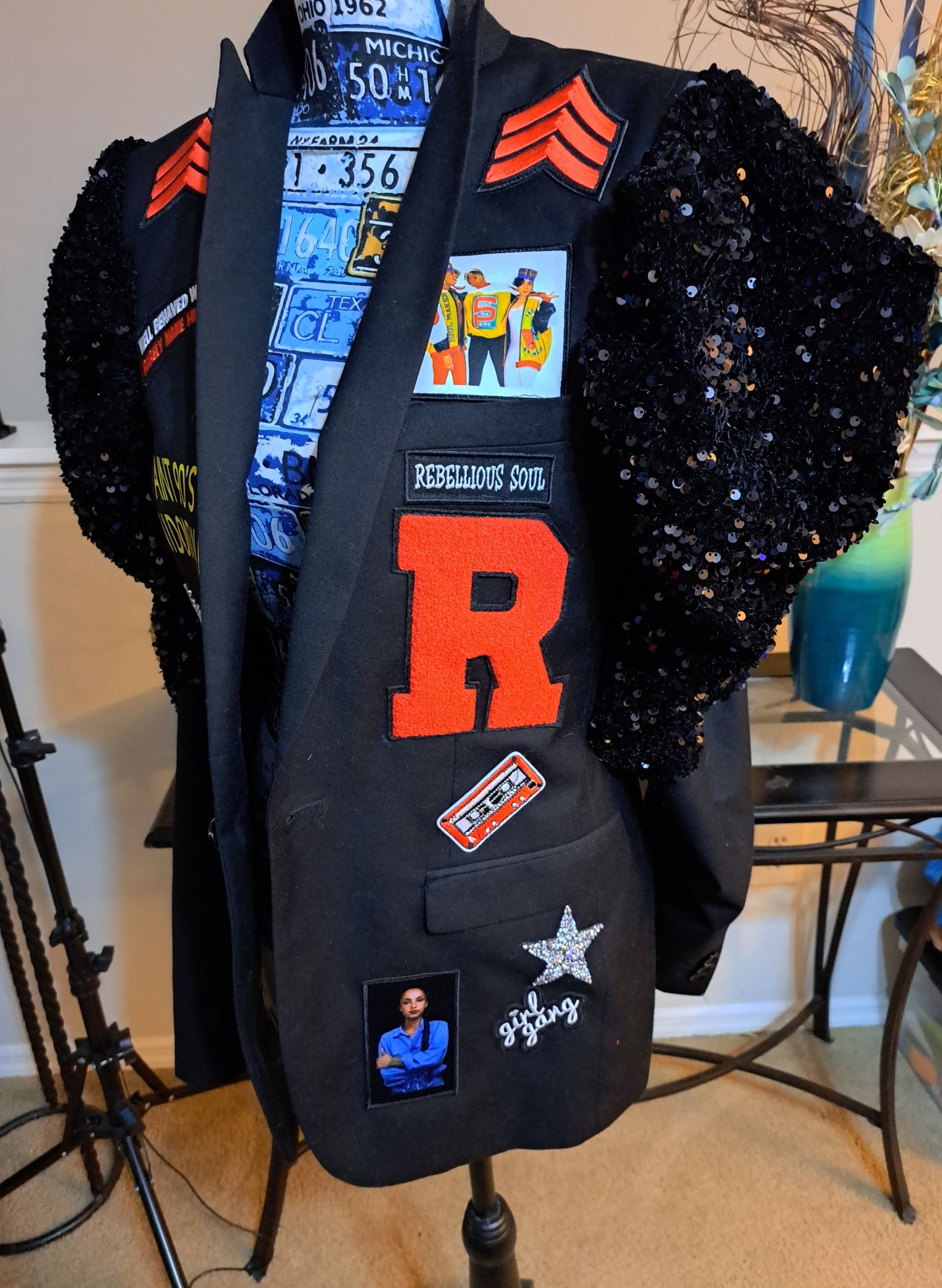 black leather ruffled coat with letter R patching in orange and other colorful patchwork