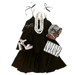 black sleeveless dress with big pearl necklaces and white pumps and black and white clutch purse on white backdrop