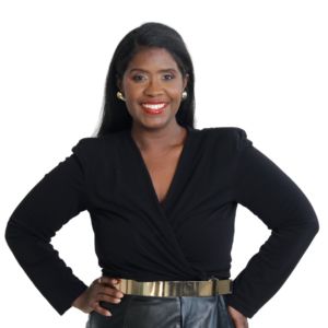 a black woman wearing a long sleeve black blouse with leather bottoms and a gold belt smiling with teeth wearing bright red lipstick