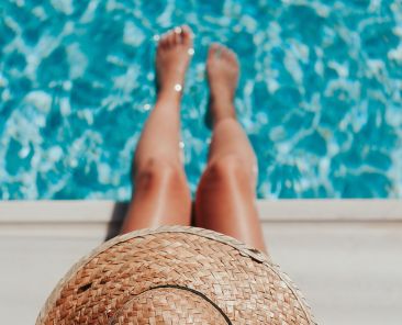 A woman wearing a hat dipping her feet in water