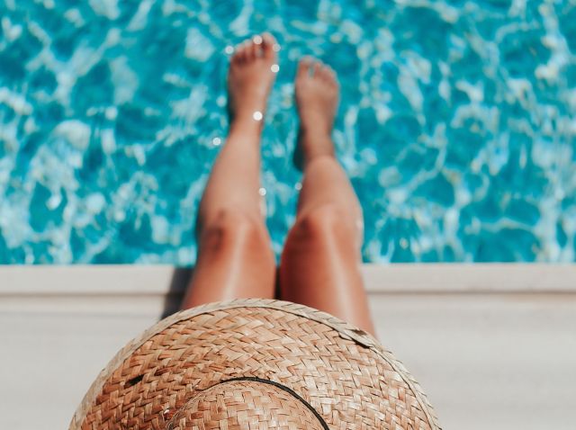 A woman wearing a hat dipping her feet in water