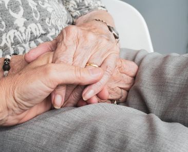 Woman holding hand with elderly person end-of-life doula