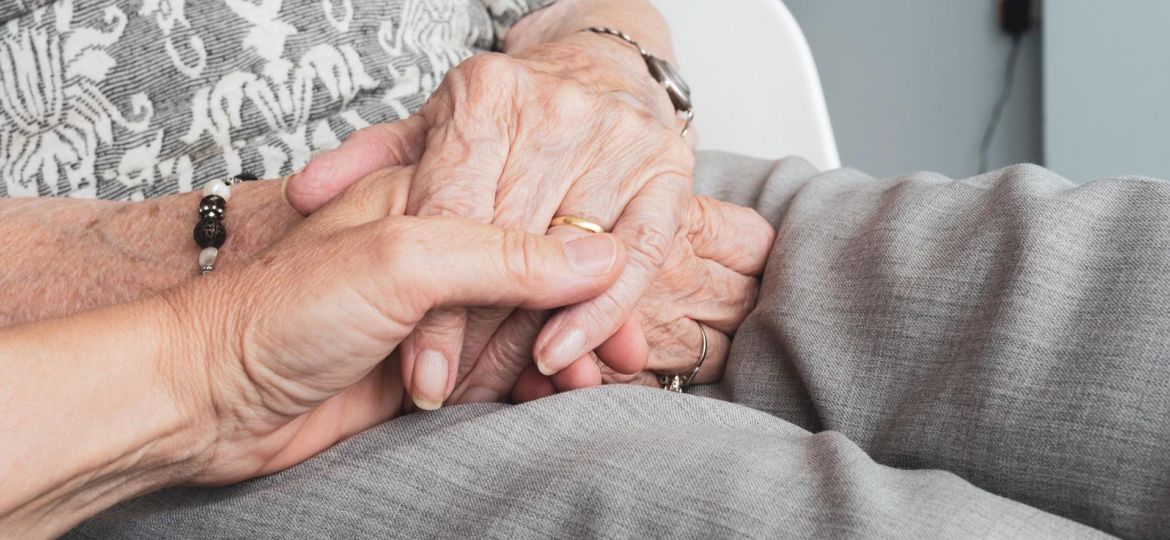 Woman holding hand with elderly person end-of-life doula