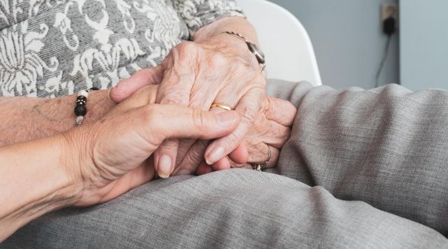 Woman holding hand with elderly person end-of-life doula