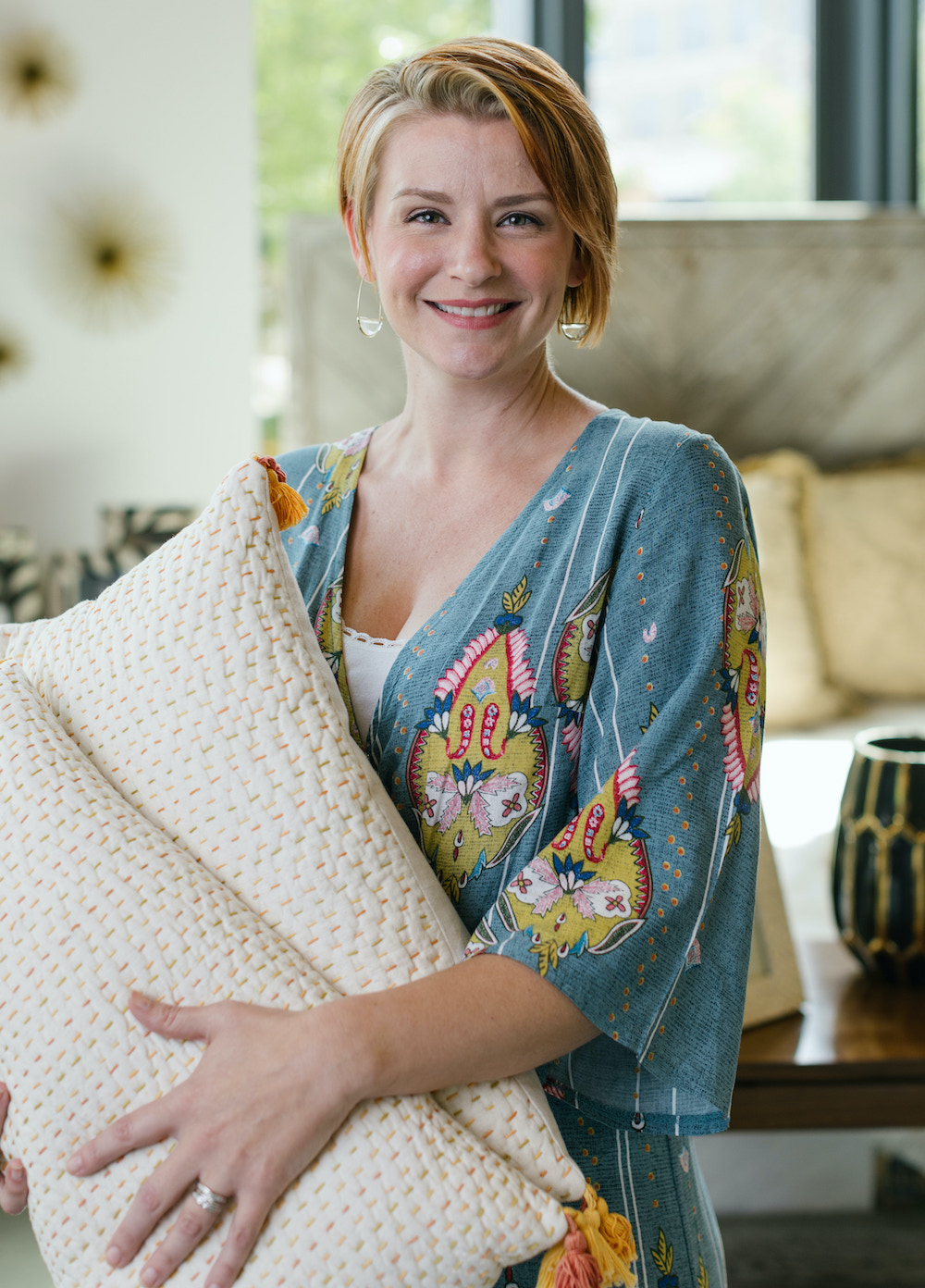 a picture of lauren taylor holding two white pillows standing in a living room