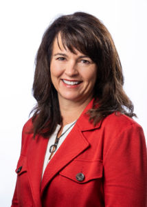 a photo of Melissa Oliver from the national bank of Indianapolis smiling with teeth wearing a bright red coat