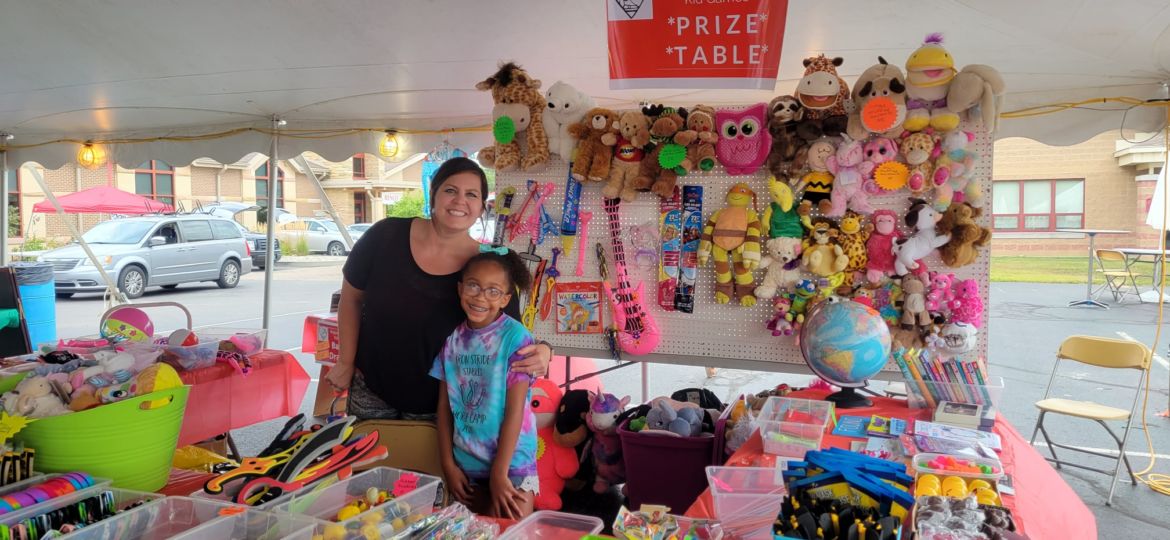 A woman and young girl working at a prize table at a festival