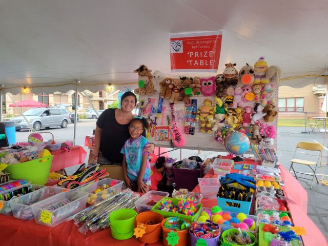 A woman and young girl working at a prize table at a festival