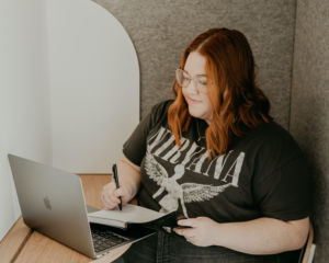 a photo of Brittney Mason writing in her journal and working on her computer