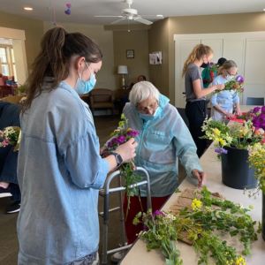 a photo of a Joy's House volunteer helping a client arrange flowers