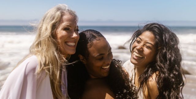 Three women laughing together on the beach