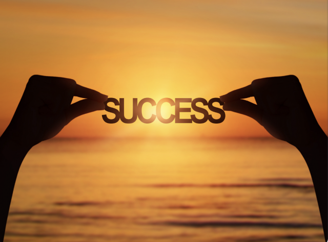 Hands holding up a success banner