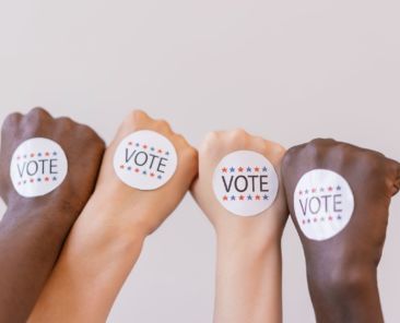 Four hands with vote stickers on them