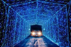 car driving through a tunnel of christmas lights