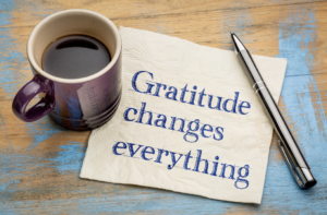 coffee cup with napkin that has "Gratitude changes everything written on it"