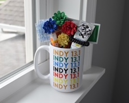 A mug with text reading "Indy 13.1" is stuffed with flowers and other goodies