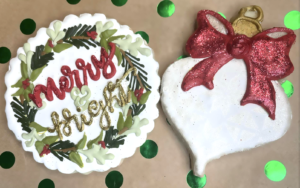 two cookies. one is shaped like an ornament, another reads "merry and bright"