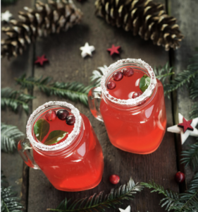 two mason jars with sugared rims are filled with a red drink that has cranberries floating in it