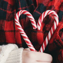Woman holding two holiday candy canes in the shape of a heart