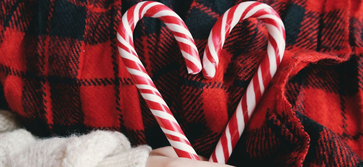 Woman holding two holiday candy canes in the shape of a heart