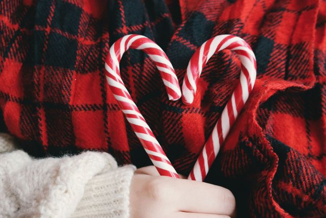 Woman holding two holiday candy canes in the shape of a heart