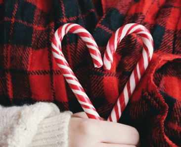 Woman holding two holiday candy canes in the shape of a heart