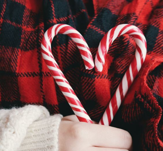 Woman holding two holiday candy canes in the shape of a heart