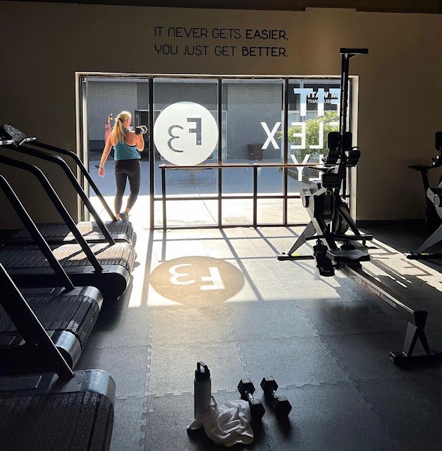Entrance of Fit Flex Fly from the inside. Various workout equipment shown. Quote above the entrance wall that says "it never gets easier, you just get better."