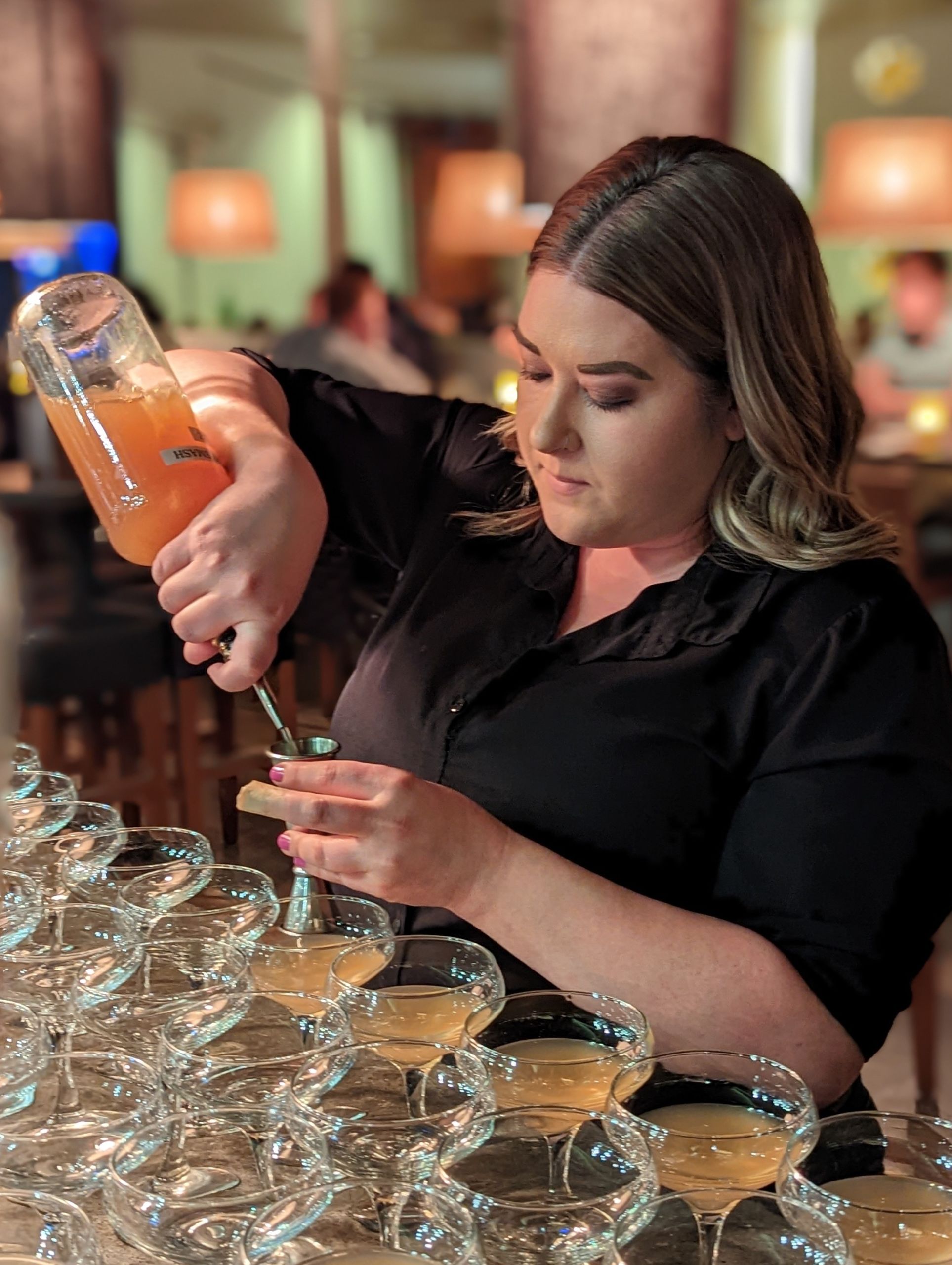 Woman bartender at Delicia pours cocktails