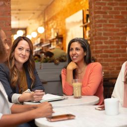 Four woman sit around a table in a coffee shop having a conversation