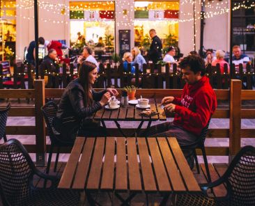 A man and a woman have dinner outside at a restaurant.