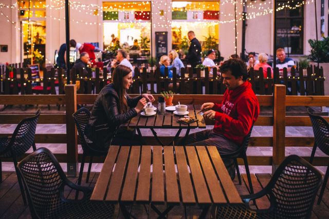 A man and a woman have dinner outside at a restaurant.