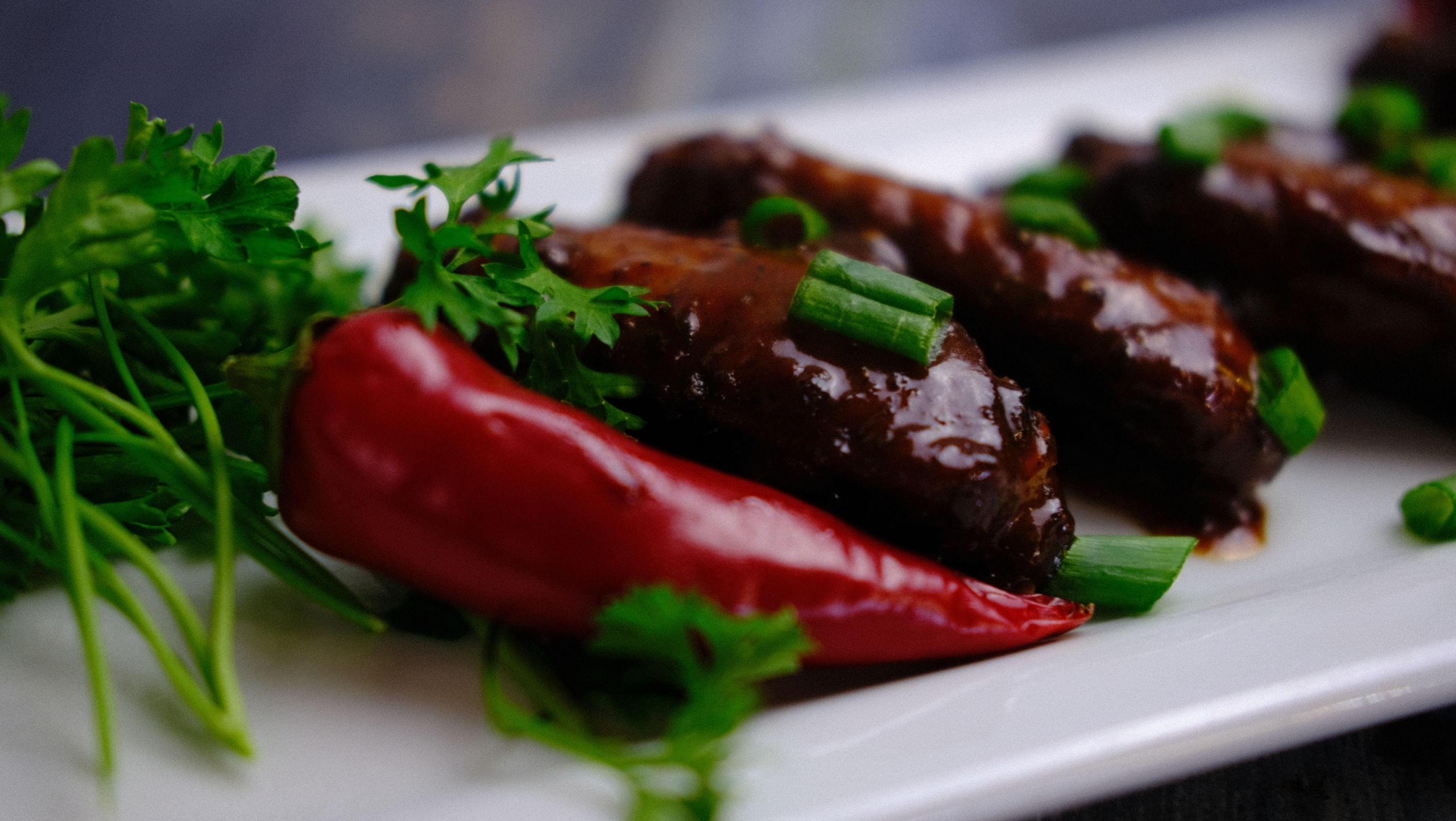 1 Island Jerk Chicken Wings (2) Jerk Chicken wings displayed with a red jalapeƱo and greens