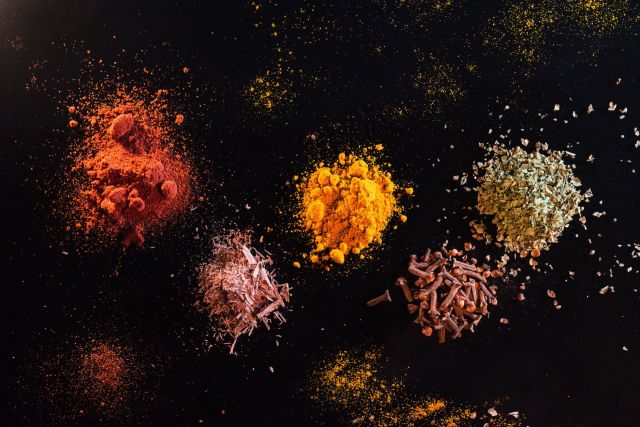 Multiple spices displayed on a black background.