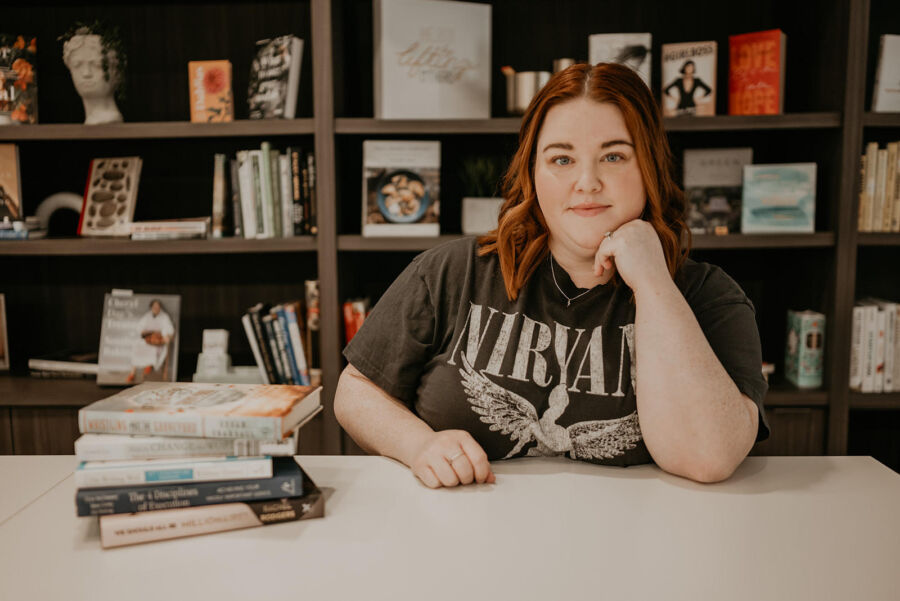 Brittney Mason sitting at a desk with a pile of books on the left