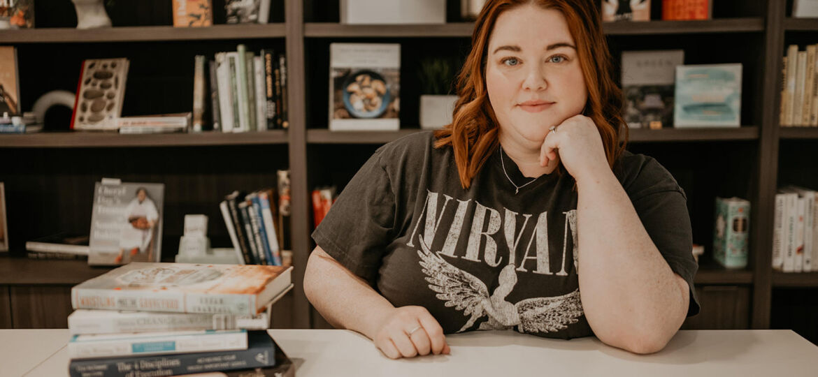 Brittney Mason sitting at a desk with a pile of books on the left