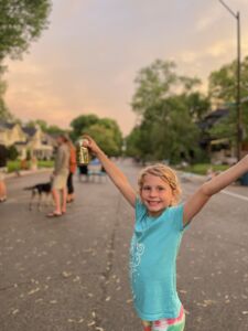 Little girl smiling with her arms up, standing in the middle of the street