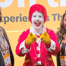 Ronald McDonald in the center with a man on his right and a woman on his left with a yellow background