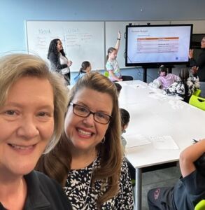 Two ladies taking a selfie with kids learning in the background. 