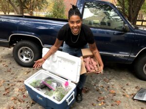 Dallas Robinson pointing to a cooler filled with vegetables and holding 