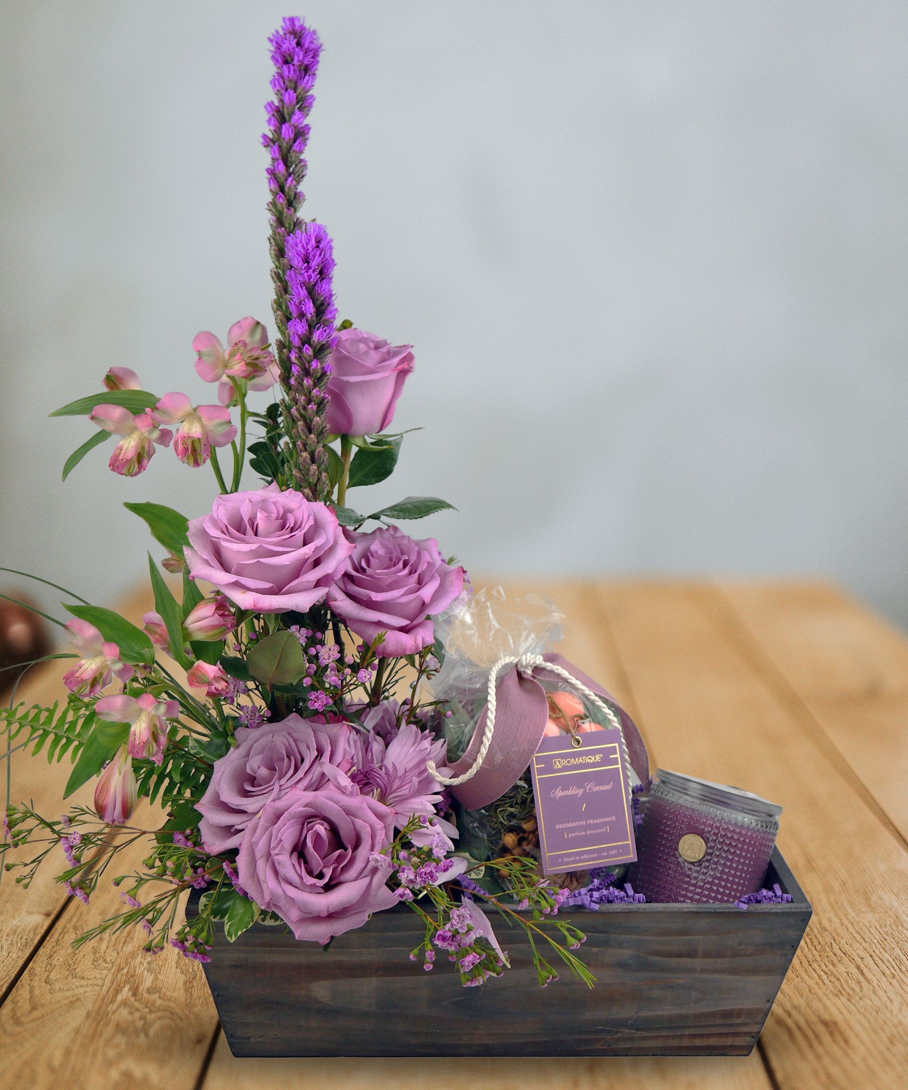 Purple flowers in a wooden box with a purple candle