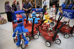 Multiple red wagons, tricycles, and Sesame Street stuffed animals. 